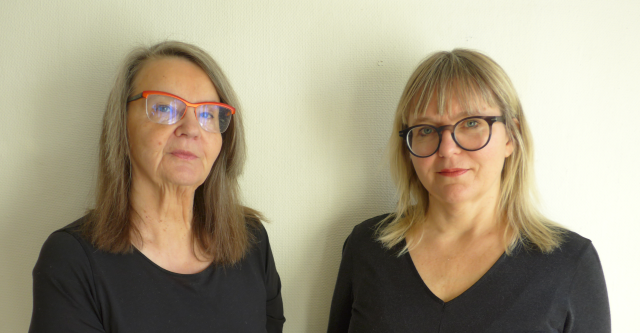 Two women with glasses and black shirts.