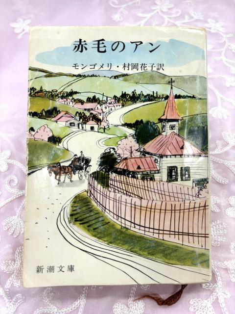 A Japanese book cover featuring an ink and watercolour illustration of a countryside village.