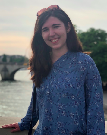 Zoe Kempf-Harris standing in front of a body of water. She is smiling. 