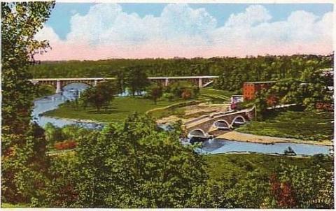 Postcard of Humber Valley. Forest is on either side of a winding river. Two bridges cross the river at different points. The sky is blue and pink.