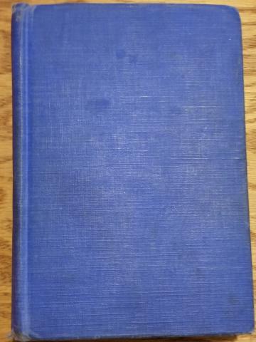 A photograph of a hardback book with a plain blue cover and no dust jacket.