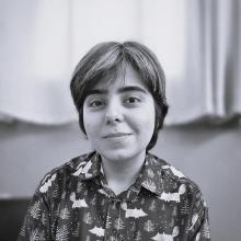 black-and-white photo of a person with short hair wearing a patterned button-up shirt